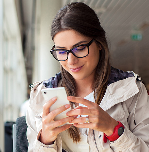 A woman in glasses holding a mobile phone